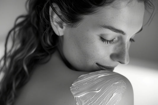 Smiling woman enjoying a serene skincare moment with nourishing cream on shoulder – representing gentle, sensorial care by Seiya Skin.